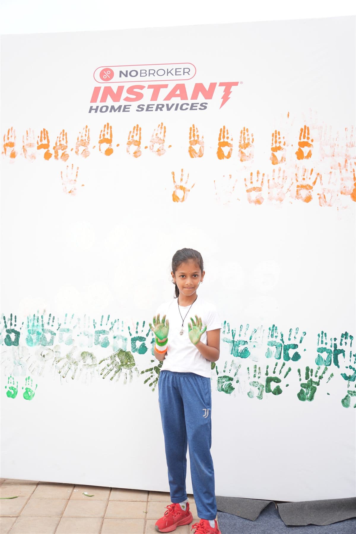 A young resident with green-painted hands after contributing to the Independence Day handprint flag wall