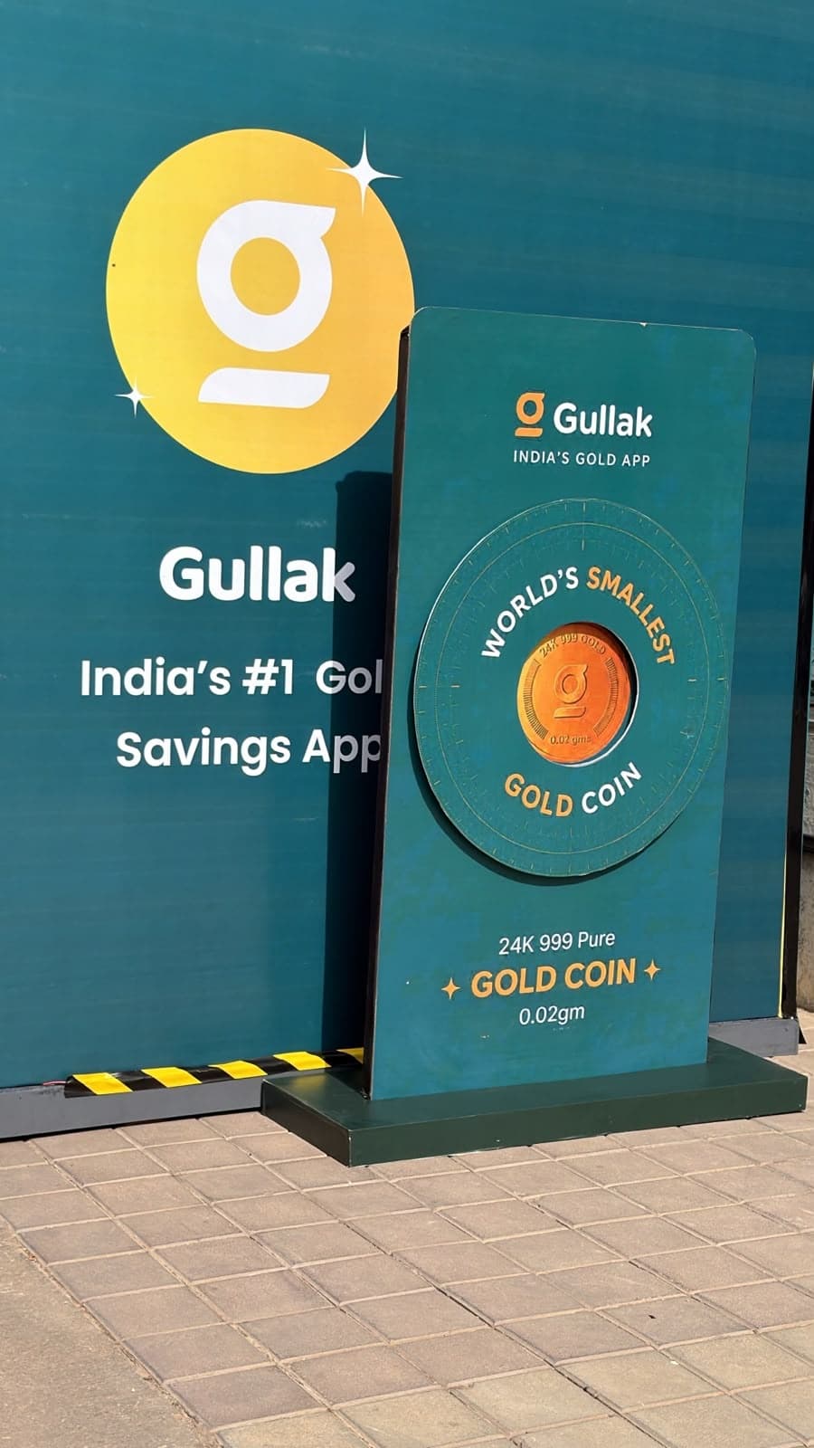World's Smallest Gold Coin 24K 999 Pure 0.02gm display pillar in front of Gullak branding