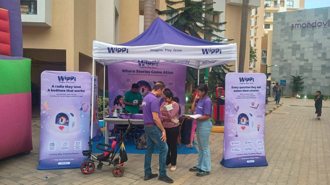 A child holding the Wippi storytelling device during a live demo, bouncy castle visible behind