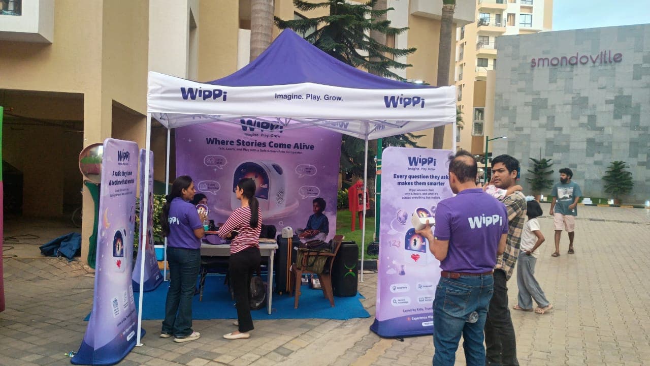A parent in conversation with the Wippi team at the branded gazebo
