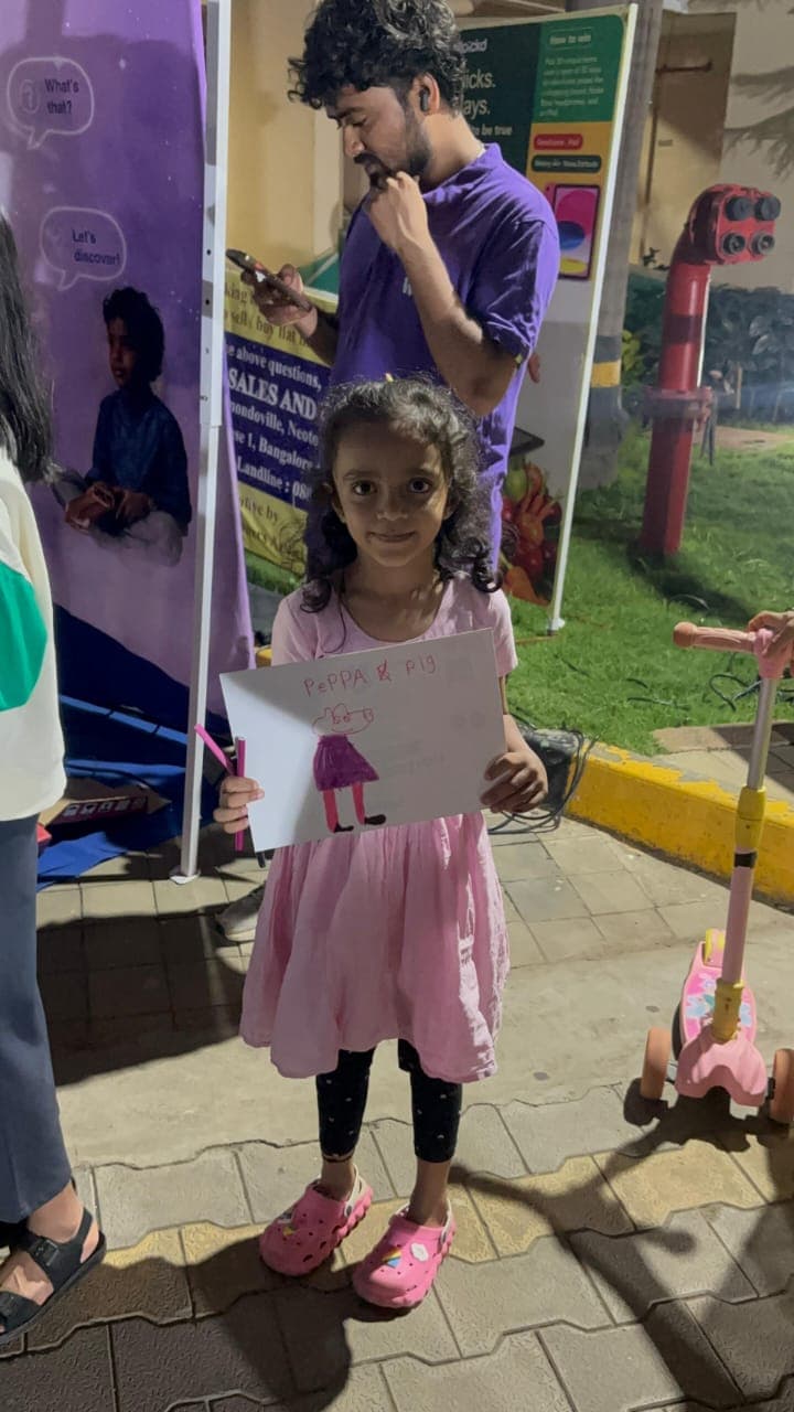 A child proudly holding her Peppa Pig drawing at the Wippi story zone after 9 PM