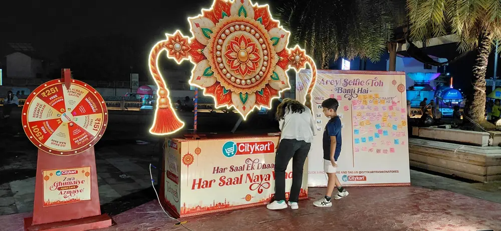 Citykart spin wheel with free shopping voucher values beside the lit Rakhi installation during the festive activation