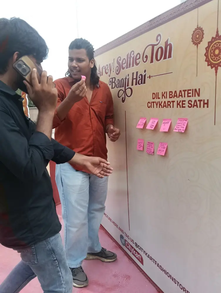 Visitors at the Citykart wish wall with wishes for sisters written on sticky notes during Raksha Bandhan