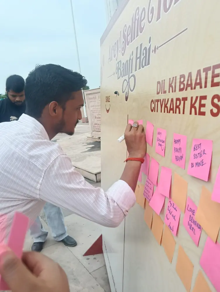 A visitor writing a Raksha Bandhan wish for his sister on the Citykart wish wall